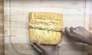 Slicing a homemade cornbread loaf on a wooden cutting board with precision and care.